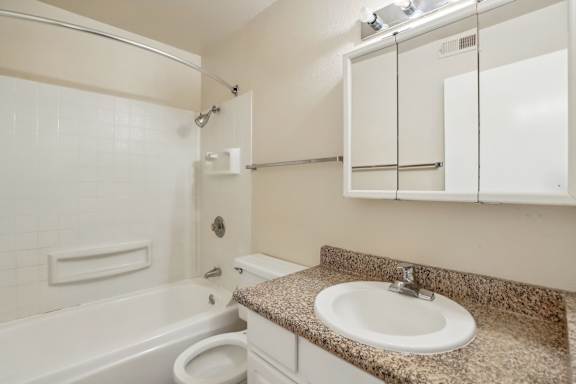 A bathroom with a sink, toilet, and bathtub.