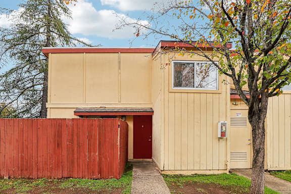 A tan building with a red door and a red fence.