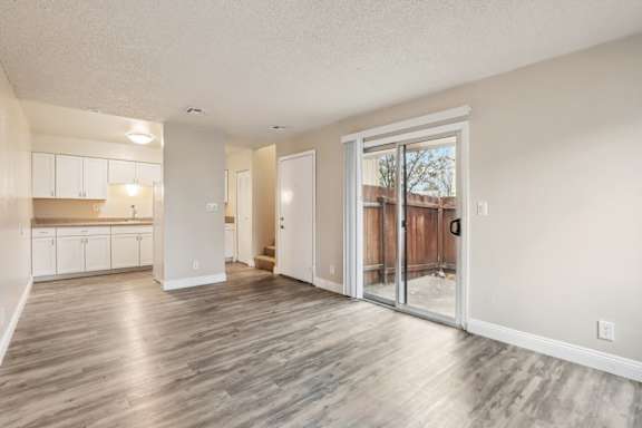 A spacious room with wooden flooring and a sliding glass door leading to a balcony.