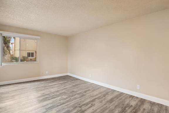 Empty room with wooden flooring and a window.