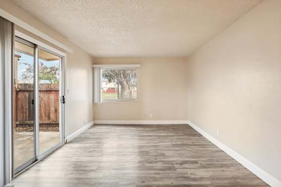 A room with a sliding glass door and wooden flooring.