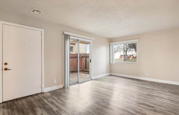 A room with a white door and a sliding glass door leading to a balcony.
