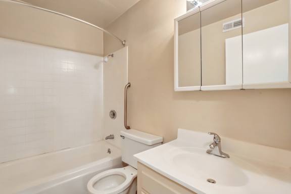 A white sink is on a counter next to a white toilet in a bathroom.
