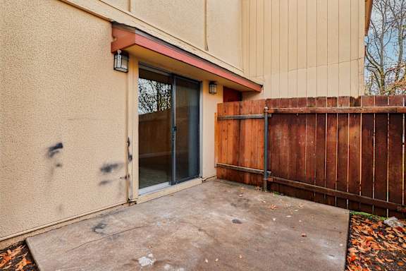 A brown fence is in front of a tan building.