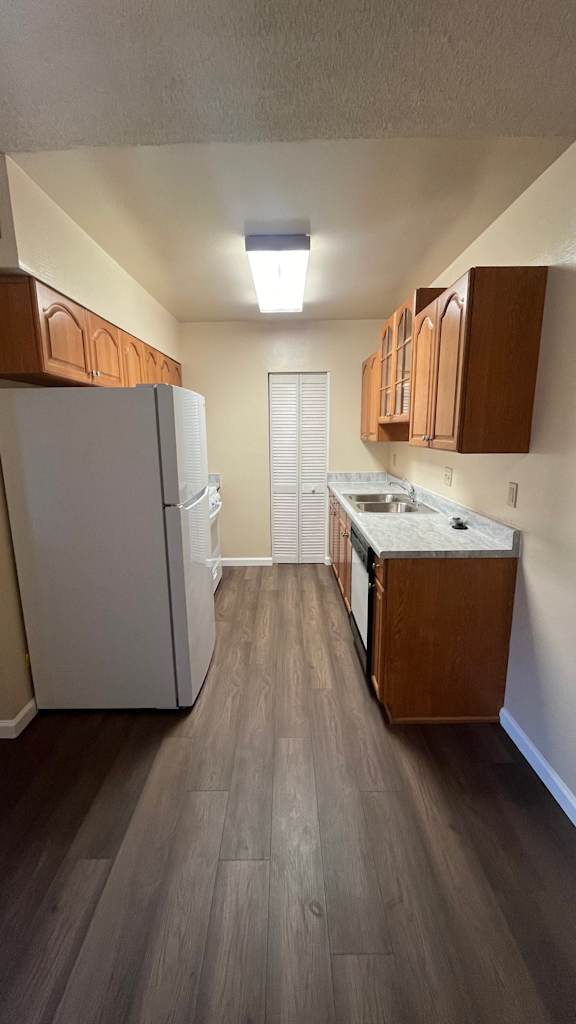 Kitchen with a white refrigerator and wooden cabinets at Vacaville Park Apartments, Vacaville, CA, California