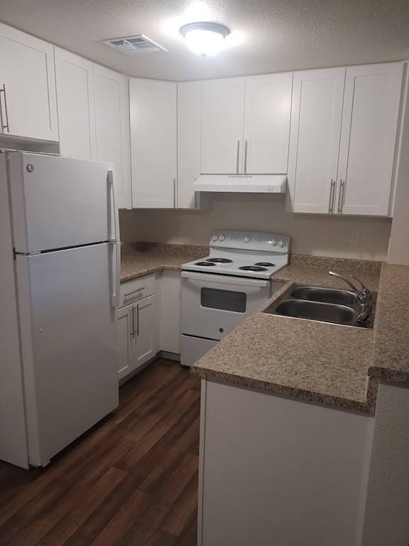 A kitchen with white cabinets and a white refrigerator.