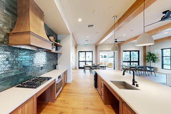 A modern kitchen with wooden cabinets and a green backsplash at The Villas at Anacapa Canyon, Camarillo