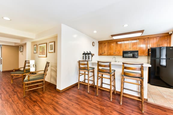 a kitchen with a bar with three chairs and a table at Village Pointe Apartments, Northridge