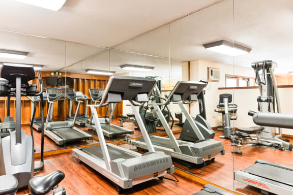 a gym with cardio equipment on the floor and mirrors at Village Pointe Apartments, Northridge, California
