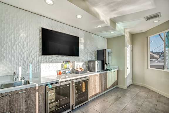 A modern kitchen with a white tile backsplash and a flat screen TV mounted above the counter.