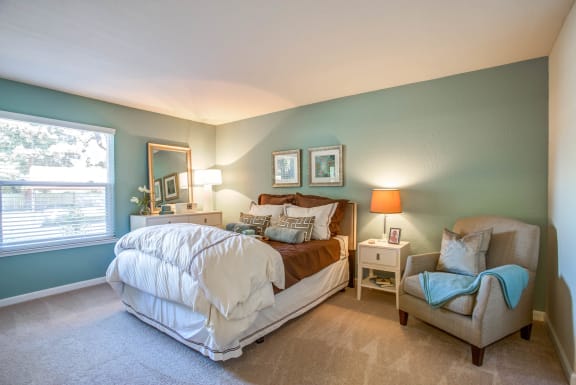 a bedroom with a bed and a chair and a window at Valley Plaza Villages, California