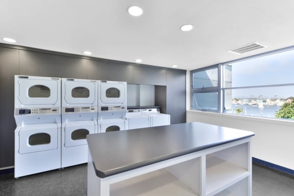 a laundry room with washers and dryers and a table at Marina Harbor, Marina del Rey