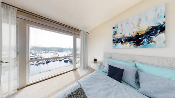 a bedroom with a large window and a bed with blue pillows  at Marina Harbor, California