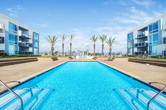 a swimming pool with apartments and palm trees in the background  at Marina Harbor, Marina del Rey, 90292