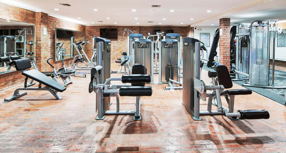 A gym with a variety of equipment including a leg press machine at The Meadows Apartments, Culver City