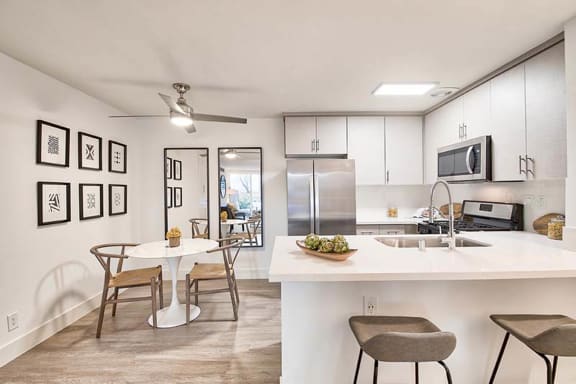A kitchen with a table and chairs in front of a refrigerator at The Meadows Apartments, Culver City, California