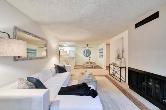 a living room with a white couch and a fireplace at The Meadows Apartments, Culver City