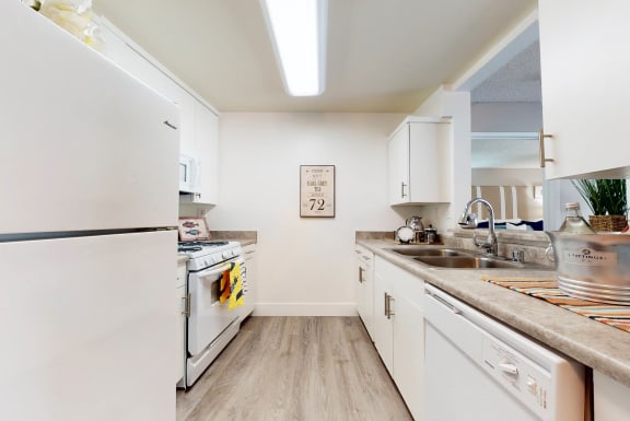 a kitchen with white appliances and white cabinets at Mountain Vista, Victorville, CA