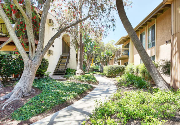 a sidewalk in front of a building with trees at Mediterranean Village Costa Mesa, California