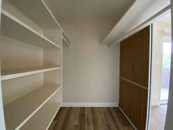 a walk in closet with white shelves and a brown closet door at Pleasanton Heights, Pleasanton, CA