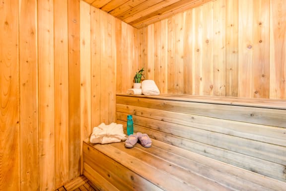 a wooden sauna with towels and a bottle on the bench