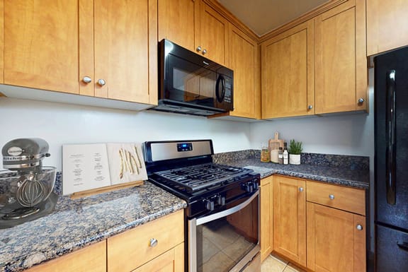 a kitchen with a stove and microwave and wooden cabinets at Sunset Barrington Gardens, Los Angeles, California