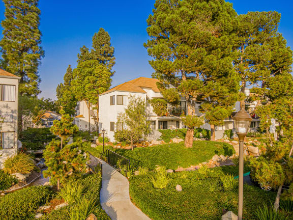 a garden with trees and a house in the background at Sendero Huntington Beach, Huntington Beach, CA 92647