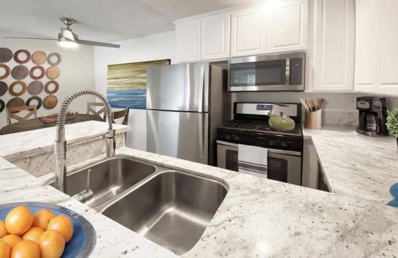 a kitchen with stainless steel appliances and granite counter tops at Sunset Barrington Gardens, Los Angeles, CA