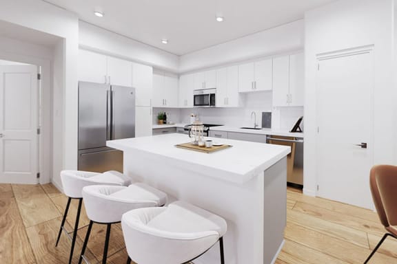 a white kitchen with three stools in front of a counter at The Villas at Anacapa Canyon, Camarillo