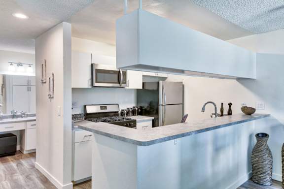 A kitchen with white cabinets and a marble countertop.