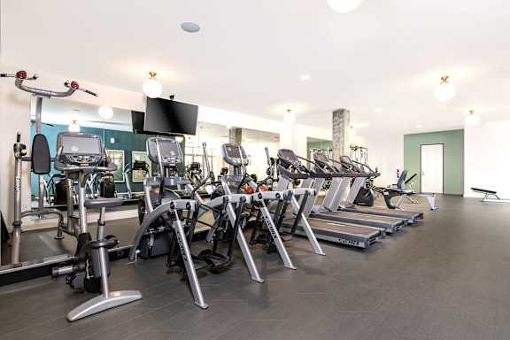 A gym with a variety of equipment including treadmills, stationary bikes, and weight machines.