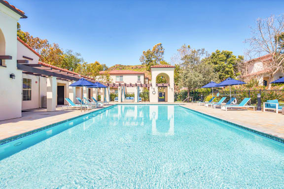 a swimming pool with chairs and umbrellas next to a house  at Mission Hills, Camarillo