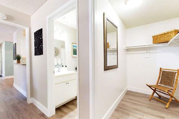 A white bathroom with a wooden chair and a mirror.