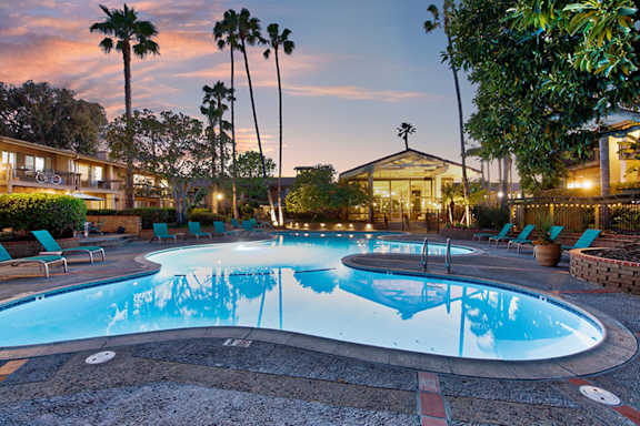 A round swimming pool surrounded by chairs and trees.