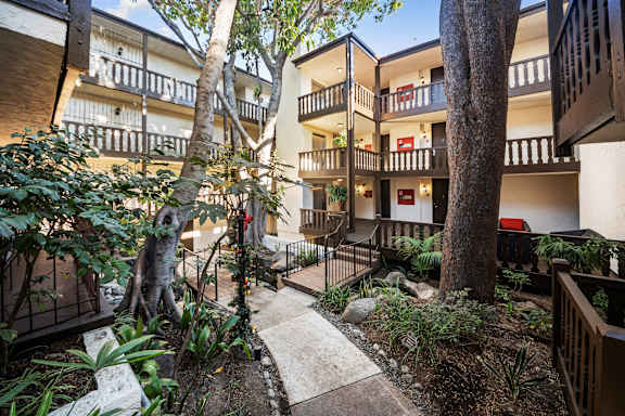 A courtyard with a tree and a cat at Mediterranean Village West Hollywood, West Hollywood