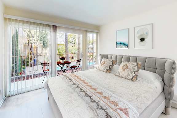 A bedroom with a large bed and a table outside.