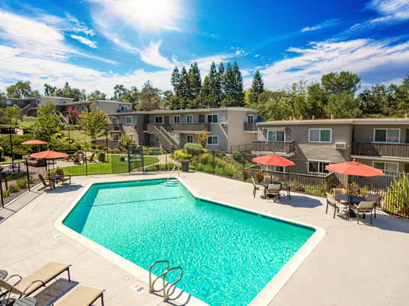 A swimming pool surrounded by lounge chairs and umbrellas in a residential area at Pleasanton Heights, Pleasanton, CA