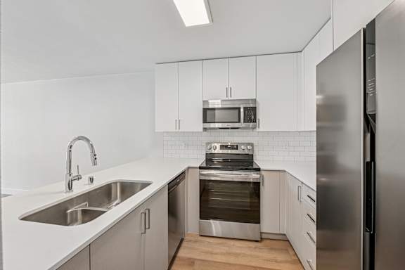 A modern kitchen with stainless steel appliances and white cabinetry.