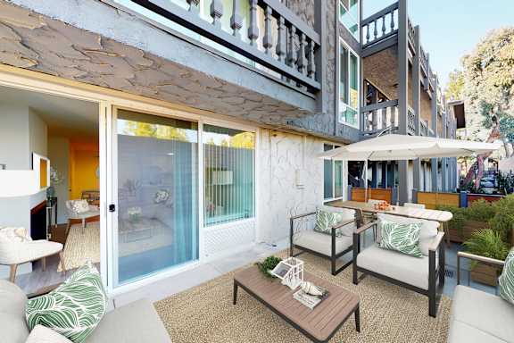 A patio with a table and chairs is surrounded by a white wall at The Meadows Apartments, Culver City , CA
