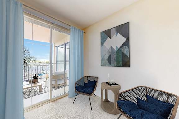 A living room with a blue chair and a painting on the wall.
