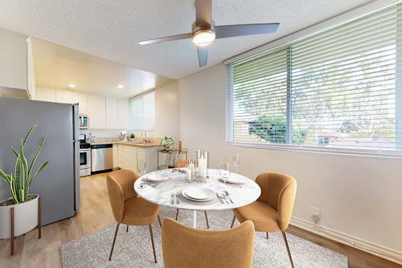 A dining room with a table set for two and a ceiling fan.