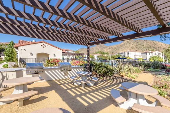 a patio with tables and chairs and a house in the background at The Villas at Anacapa Canyon, Camarillo, California