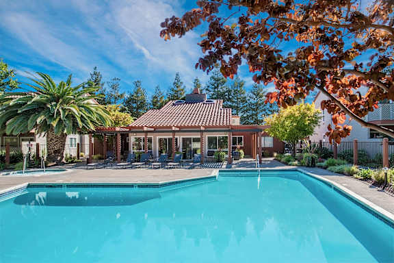 A swimming pool surrounded by trees and a building with a red roof at Valley Plaza Villages, Pleasanton, California