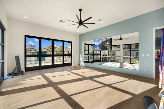 A room with a ceiling fan and a large window overlooking a balcony at The Villas at Anacapa Canyon, Camarillo