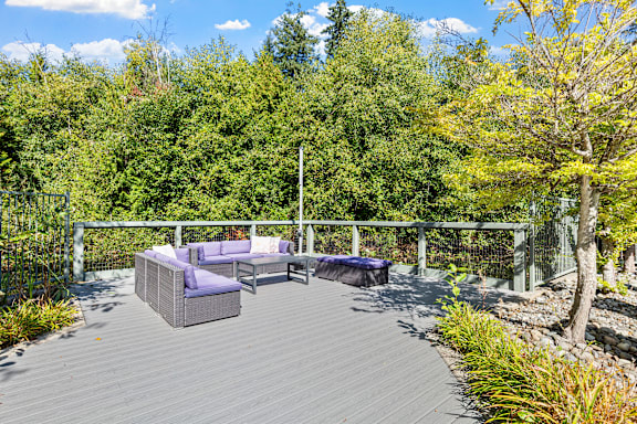 A grey deck with a purple couch and a white pole.