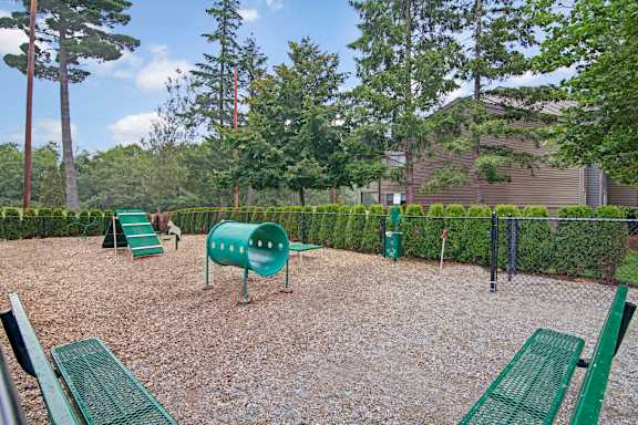A playground with green equipment and a gravel ground.