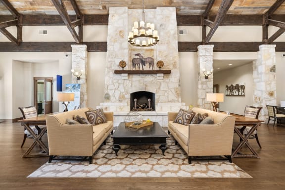 a living room with couches and a table and a fireplace at Lakeline East Apartments, Texas