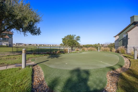 a putting green in front of a building with a fence at The Fairways at Star Ranch, Hutto, TX, 78634