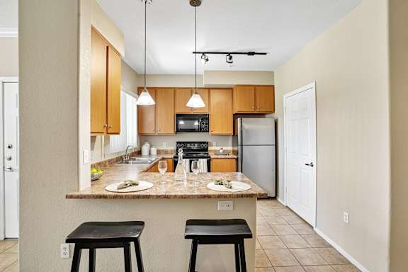 A kitchen with a table and two stools.