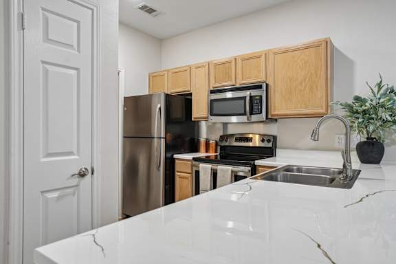 A kitchen with a white counter top and wooden cabinets.